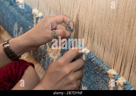 Frau händigt den Webteppich am Webstuhl in Margilan, Usbekistan, aus. Stockfoto