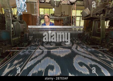 Frau arbeitet und webt Seidenstoff in der Seidenfabrik in Margilan, Usbekistan. Stockfoto