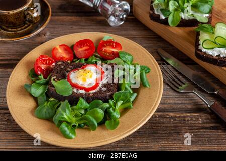 Köstliche offene Sandwiches auf Roggenbrot mit Hüttenkäse, Spinat mikrogrün, Gurke und gebackenen Wachteleiern auf Küchenbrett im rustikalen Woode Stockfoto