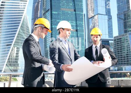 Architektenteam vergleicht Wohnungsbauprojekt mit dem Gebäude über Wolkenkratzer-Hintergrund Stockfoto