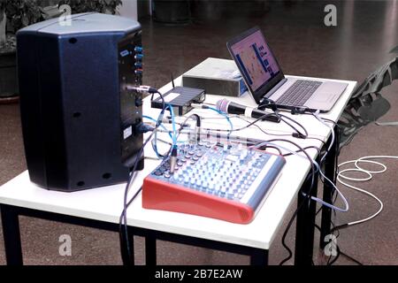 Soundbox, Audio-Mixer und Computer, die vor dem Start eines Karaokes auf einen Tisch gelegt wurden Stockfoto