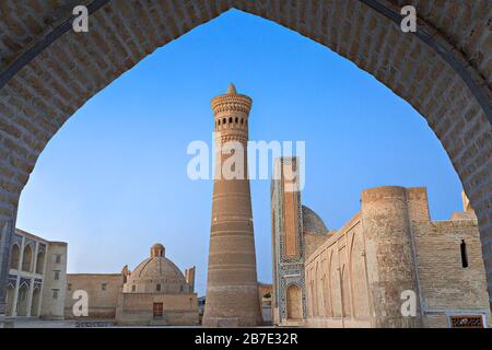 Poi-Kalon-Moschee und Minarett, bei Sonnenaufgang, durch einen Bogen, in Buchara, Usbekistan Stockfoto