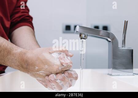 Zwei Hände eines Mannes, der in einem weißen, modernen Haufen mit Seifenschaum und Wasser, Virenschutz, Hygiene- und Hautpflegekonzept waschen hat, Platz für Text kopieren Stockfoto