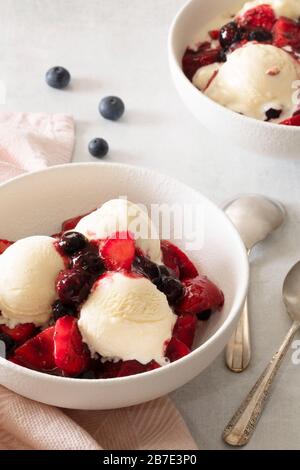 Portionen gemischter Beeren-Coulis mit Vanilleeis. Stockfoto
