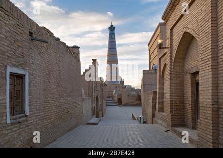 Blick über eine enge Straße mit Minarett im Hintergrund in der antiken Stadt Khiva in Usbekistan Stockfoto