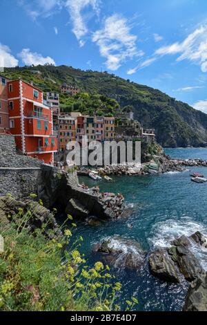 RIOMAGGIORE, ITALIEN - 15. August 2019: Blick auf Riomaggiore und das Meer und die Klippen an der Cinque Terre an einem sonnigen Tag Stockfoto