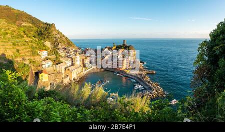 Panorama-Blick auf Vernazza und den Ozean bei Sonnenuntergang auf der Cinque Terre von oben mit blauem Himmel Stockfoto