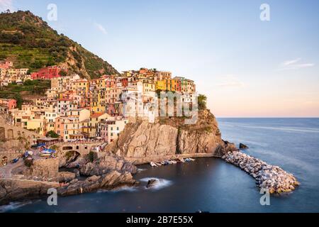 Manarola als eines der Cinque Terre Dörfer mit Boot bei Sonnenuntergang Stockfoto