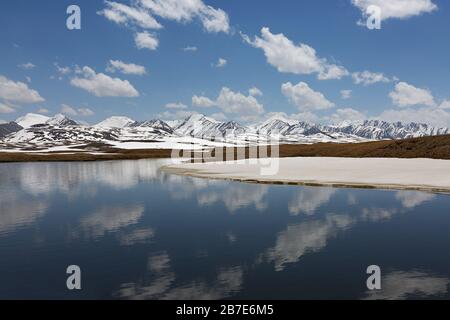 Bergsee auf den Bergen in Barskaun, mit Spiegelungen im Wasser in Kirgisistan Stockfoto