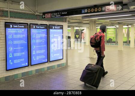 Man spaziert durch MTA-Schilder, die Informationen darüber anzeigen, wie man vermeiden kann, und verhindert die Ausbreitung von Coronavirus in der leeren U-Bahn-Station Times Square, NYC, 15. März 2020 Stockfoto