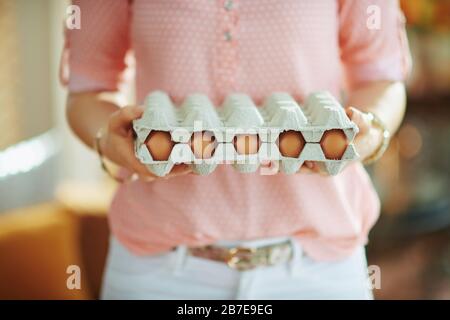 Nahaufnahme der Frau im Haus am sonnigen Frühlingstag mit großer Eierkartonschachtel. Stockfoto