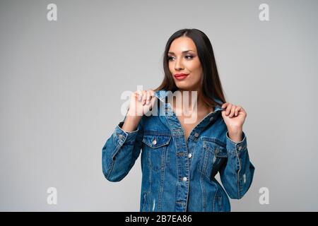 Schöne kaukasische Mädchen Jeansjacke im Studio posiert auf weißem Hintergrund. Cute brunette. Denim mode Elegante rote Lippen Make-up. Junge erwachsene Frau s Stockfoto