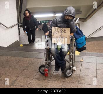 Behinderte Frau, die um Hilfe bittet, platziert sich strategisch in der Mitte eines Fußgängertunnels der U-Bahn in Grand Central Station, New York City. Stockfoto