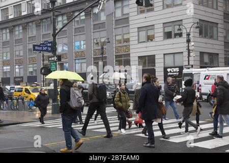 In der morgendlichen Hauptverkehrszeit in der 34th Street und 8th Avenue neben einer großen U-Bahn-Station und der Penn Railroad Station grüßt der Regen die Leute, die in Manhattan zur Arbeit kommen. NYC. Stockfoto