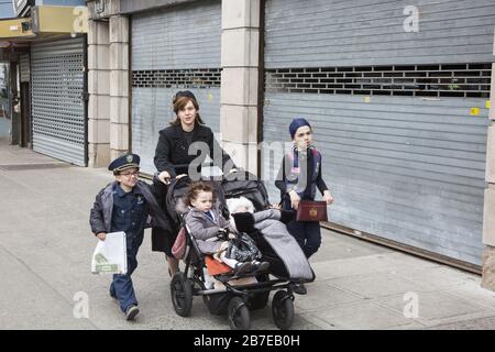 Die orthodoxe jüdische Gemeinde im Borough Park Brooklyn feiert den festlichen Urlaub von Purim, indem sie Kostüme trägt, Armen spendet, leckere Speisen isst und im Allgemeinen eine gute Zeit hat. Die Leute auf der 13th Avenue. Purim wird jedes Jahr am 14. Des hebräischen Monats Adar gefeiert. Es erinnert an die Errettung des jüdischen Volkes im alten Perserreich aus Hamans Handlung "alle Juden, jung und alt, Säuglinge und Frauen, an einem einzigen Tag zu vernichten, zu töten und zu vernichten", wie in der Megillah (Buch Esther) festgehalten. Stockfoto