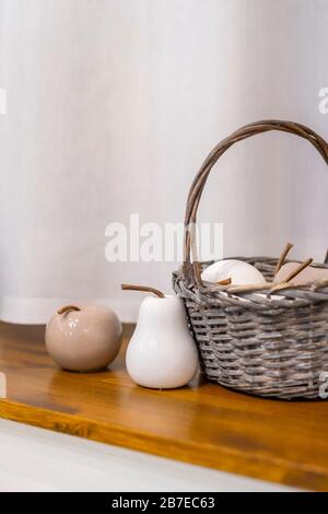 Stillleben - ein Korb aus Keramikfrüchten aus Porzellan in neutralen Farben auf einem Fensterschweller. Stockfoto