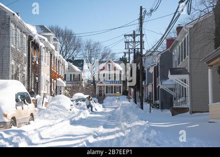 Annapolis Street Szene am sonnigen Tag nach blizzard mit Schnee, der auf Straßen und Gehwegen gehüpft wird, entfernter Fußgänger, der in Schnee schaufelt und geht Stockfoto