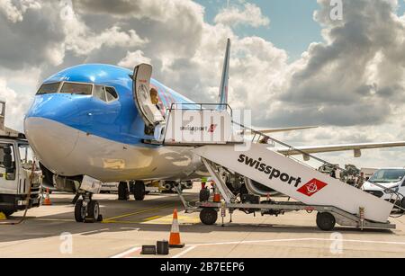 BRISTOL, ENGLAND - AUGUST 2019: Die Passagierschritte des Umschlagunternehmens SWISSPORT sind mit einem TUI Boeing 737-Urlaubsjet am Flughafen Bristol verbunden. Stockfoto