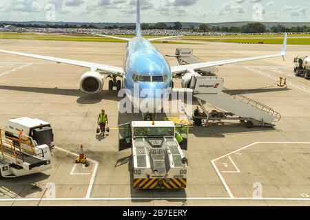 FLUGHAFEN BRISTOL, ENGLAND - AUGUST 2019: TUI Boeing 737 Jet umgeben von Bodenausrüstung am Flughafen Bristol. Ein Flughafenschleppen steht im Vordergrund Stockfoto