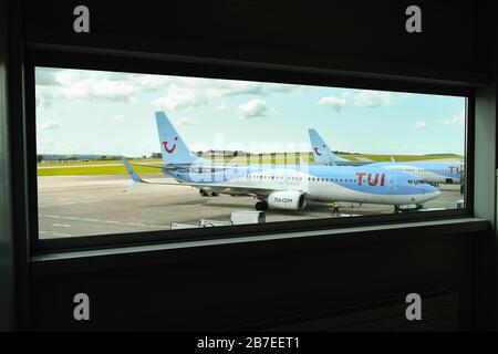 FLUGHAFEN BRISTOL, ENGLAND - AUGUST 2019: Blick auf die TUI Boeing 737-Urlaubsflugzeuge, eingerahmt von einem Fenster im Flughafenterminal am Flughafen Bristol. Stockfoto