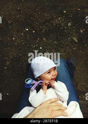 Vertikale Aufnahme eines Babys, das auf dem einer Person liegt Beine über dem Boden Stockfoto