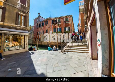 Venedig, Italien - 16. MAI 2019: Touristen ruhen auf dem Steindamm des Kanals - das ist Venedig Stockfoto