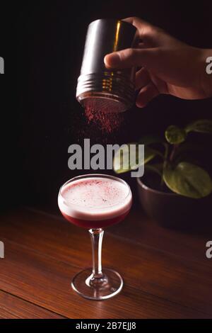 Himbeere alkoholischer Cocktail in einem Glas mit Schaum, mit gefriergetrockneten Himbeeren bestreut. Stockfoto