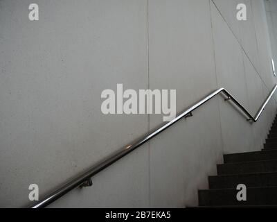 Langer Schuss silbernes Metall Handgeländer an einer Wand Neben der Treppe in schwarz und weiß Stockfoto