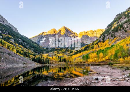 Maroon Bells See bei Sonnenaufgang in Aspen, Colorado mit felsigen Bergspitzen und Schnee im Oktober 2019 Herbst und lebhaften Bäumen reflektieren auf Wate Stockfoto