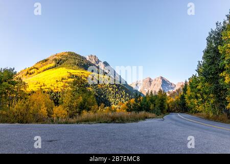 Aspen, Colorado Maroon Bells Mountains im Oktober 2019 und lebhafte Bäume Laub Herbst und Himmel entlang der leeren Straße Stockfoto