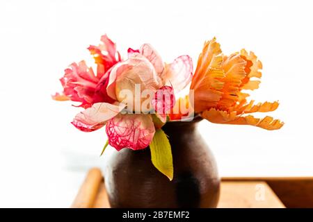 Rosa und orangefarbene Tulpen Blumen Makro Close-Up-Bouquet Anordnung in Vase Topfpflanze in der Nähe der Wandvorhänge Jalousien in weißem Hintergrund Stockfoto