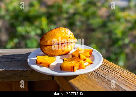 Nahaufnahmen von orangegelbem sternenfrucht auf Platte auf Decksgeländerlineal außen mit lebhaften Farben Stockfoto
