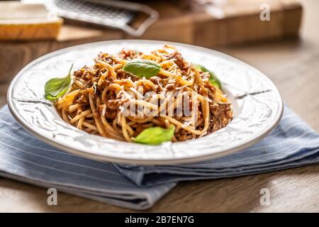 Italienische Pasta Spaghetti bolognese serviert auf weißem Teller mit Parmesankäse und Basilikum Stockfoto