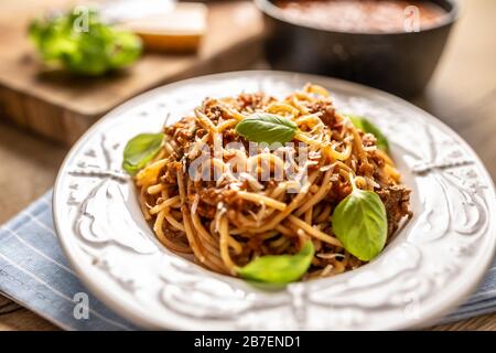 Italienische Pasta Spaghetti bolognese serviert auf weißem Teller mit Parmesankäse und Basilikum Stockfoto