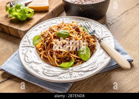 Italienische Pasta Spaghetti bolognese serviert auf weißem Teller mit Parmesankäse und Basilikum Stockfoto