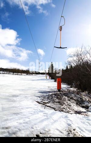 Stilles T-Bar-Surface-Lift auf leerer Piste, Konzept für das Ende der Skisaison, Abhang mit verschwindendem Schnee, sonniger Winter oder Frühlingstag Stockfoto