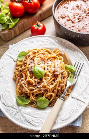 Italienische Pasta Spaghetti bolognese serviert auf weißem Teller mit Parmesankäse und Basilikum Stockfoto