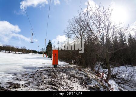 Stilles T-Bar-Surface-Lift auf leerer Piste, Konzept für das Ende der Skisaison, Abhang mit verschwindendem Schnee, sonniger Winter oder Frühlingstag Stockfoto