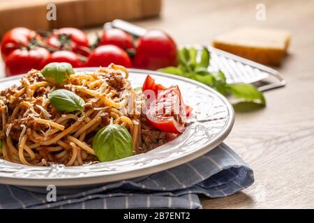 Italienische Pasta Spaghetti bolognese serviert auf weißem Teller mit Parmesankäse und Basilikum Stockfoto