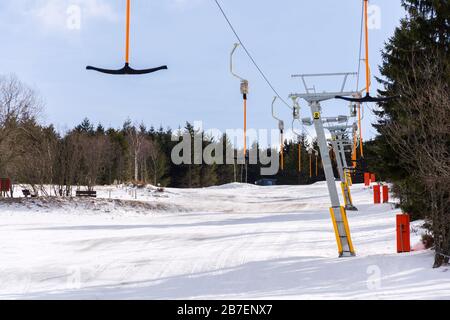 Stilles T-Bar-Surface-Lift auf leerer Piste, Konzept für das Ende der Skisaison, Abhang mit verschwindendem Schnee, sonniger Winter oder Frühlingstag Stockfoto