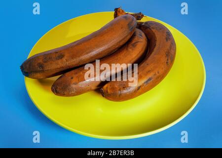 Bananenbündel mit hellbrauner Schale auf blauem Grund in der Nähe. Stockfoto