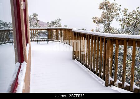 Haus Hausgrundstück mit Blick auf Boden und Herbstlaub auf Bäumen mit schneebedeckten Blättern und Stuhl am Fenster Stockfoto