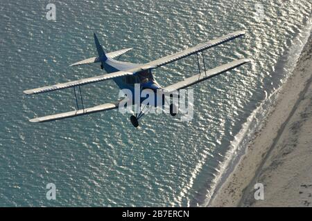 Ein Luftbild eines schwedischen registrierten de Havilland DH.87 Hornet Moth, auf dem Flug, der sich einem Strand nähert. Stockfoto