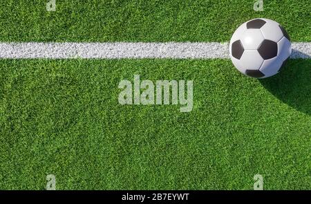 Fußball- oder Fußballball auf einer weißen Linie auf grünem Rasen eines Sportplatzes, der seitlich platziert wird und von oben aus einen Kopierraum sieht Stockfoto