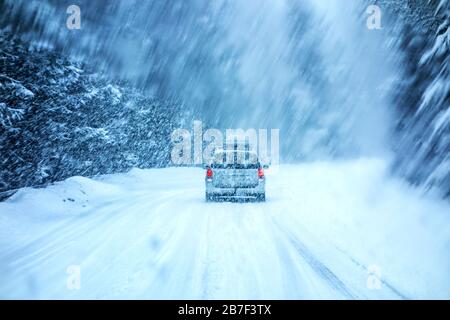 Auto fährt im Winter Schneesturm durch eine Windschutzscheibe, die mit verschwommenen Schneeflocken bedeckt ist. Stockfoto