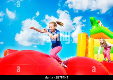 Glückliche kleine Mädchen haben viel Spaß beim Springen von Ball zu Ball auf einem Schloss aufpumpen. Stockfoto