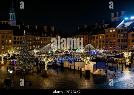 Warschau, Polen - 17. Dezember 2019: Altstadt-Marktplatz Warszawa nachts mit Weihnachtsbeleuchtung und Neujahrsbaum mit Menschen Skat Stockfoto