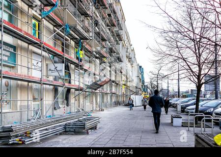 Warschau, Polen - 19. Dezember 2019: Straße Marszalkowska mit Menschen, die auf dem Bürgersteig durch Gerüste auf dem Gebäude in der Warszawa-Innenstadt in eveni laufen Stockfoto