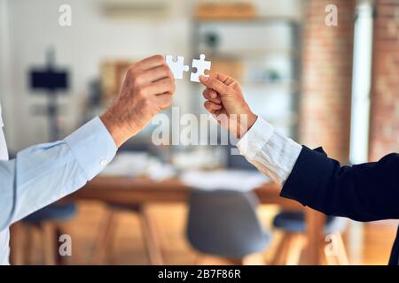 Zwei Hände, die versuchen, paar Puzzleteil im Büro zu verbinden Stockfoto