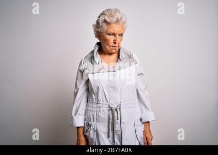 Ältere schöne grauhaarige Frau mit legerer Jacke, die über weißem Hintergrund steht, skeptisch und nervös, aufgefrannt wegen des Problems. Negati Stockfoto